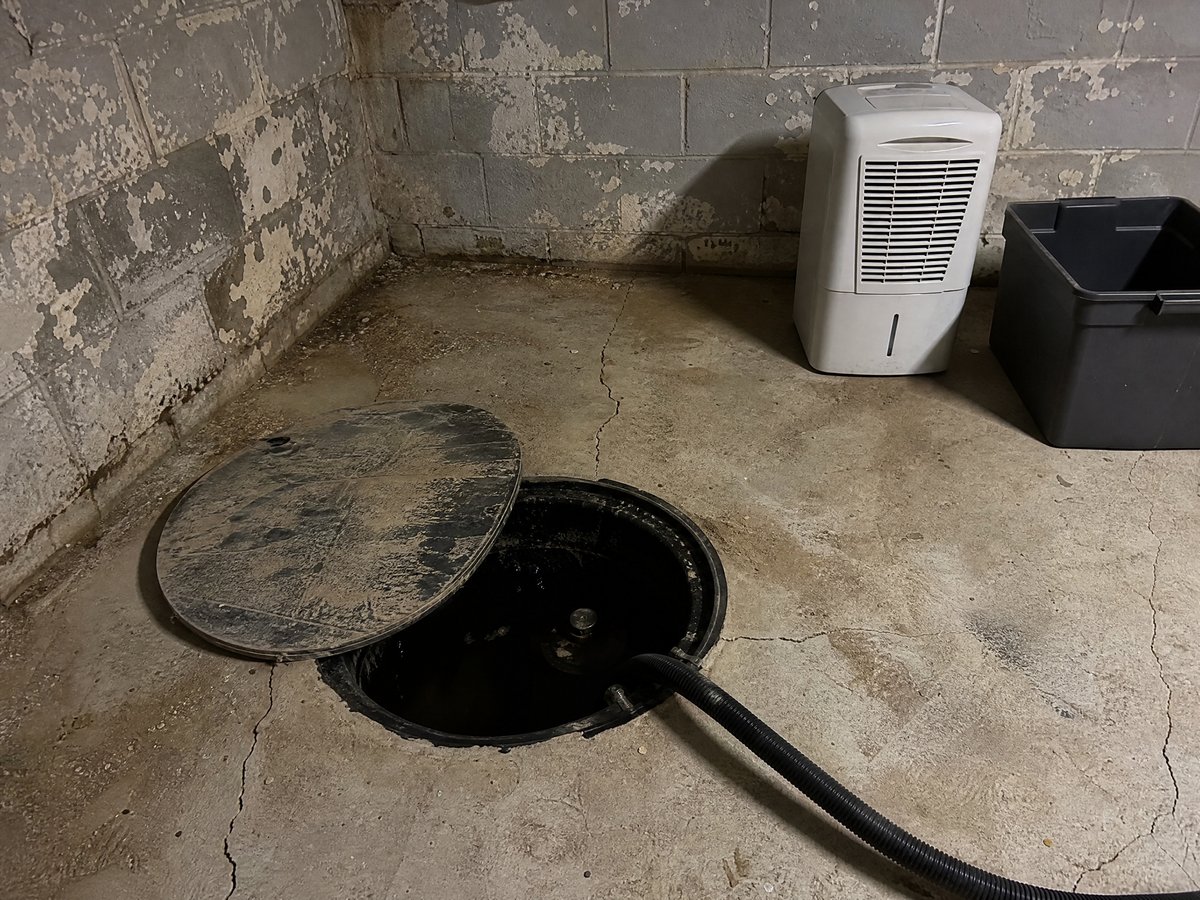 Sioux Falls basement with open sump crock and unsealed floor cracks before radon mitigation